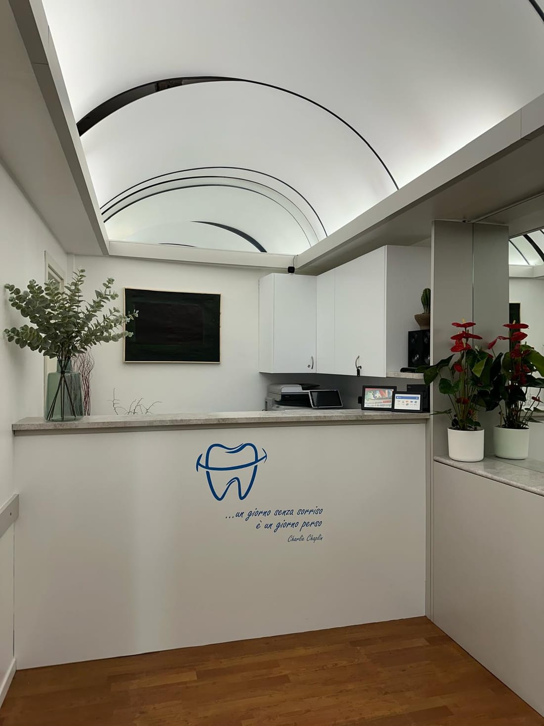 La reception dello studio, con il soffitto a volta illuminato e il logo del dente sul bancone